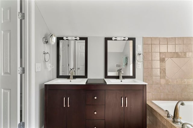 bathroom featuring a relaxing tiled tub and vanity