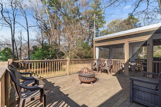 deck featuring a sunroom and a fire pit