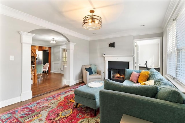 living room featuring hardwood / wood-style floors, ornate columns, crown molding, and an inviting chandelier