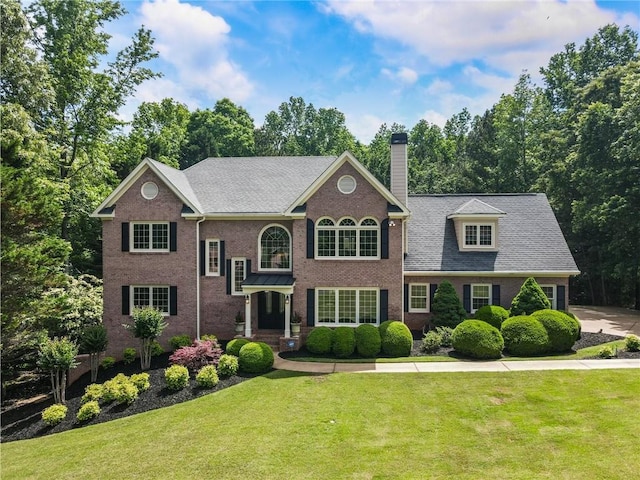135 Stone Orchard Ct, Milton, GA 30004 - view of front of house with a chimney, a front lawn, brick siding, and view of scattered trees