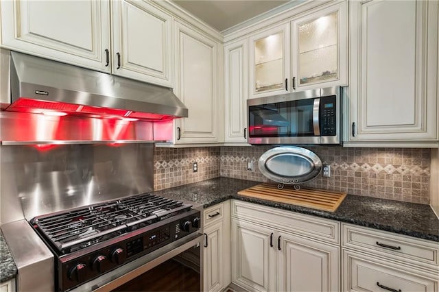 135 Stone Orchard Ct, Milton, GA 30004 - kitchen with appliances with stainless steel finishes, under cabinet range hood, backsplash, glass insert cabinets, and dark stone countertops