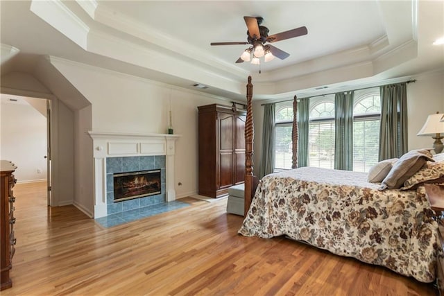 135 Stone Orchard Ct, Milton, GA 30004 - bedroom featuring a raised ceiling, crown molding, light wood-style flooring, a fireplace, and a ceiling fan