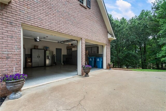 135 Stone Orchard Ct, Milton, GA 30004 - garage featuring stainless steel fridge with ice dispenser, concrete driveway, and a garage door opener