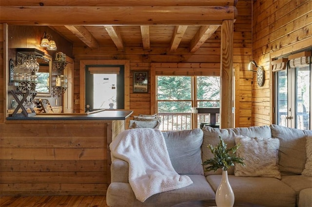 living room with beam ceiling, wooden walls, wood-type flooring, and a wealth of natural light