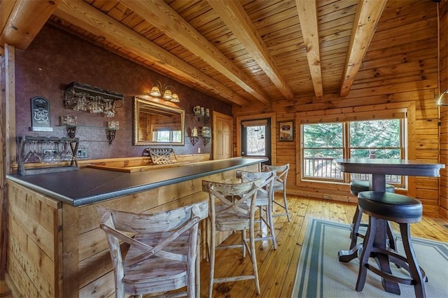 bar with wood walls, beam ceiling, light hardwood / wood-style floors, and wooden ceiling