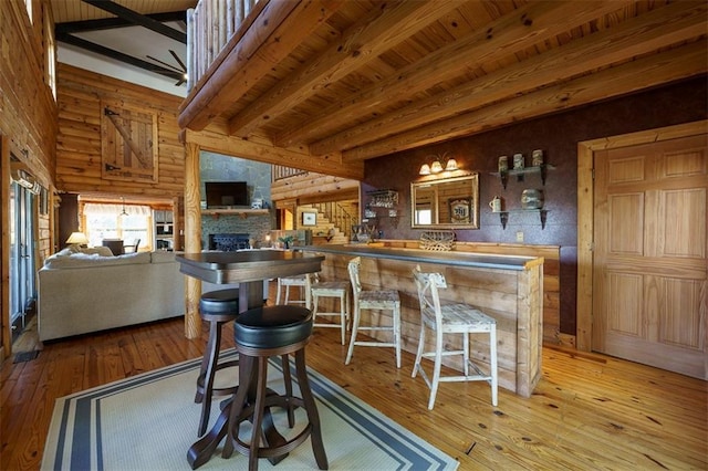 bar with beam ceiling, a fireplace, light hardwood / wood-style floors, and wooden ceiling