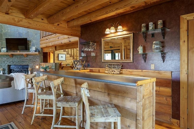 bar featuring wood-type flooring, a fireplace, beam ceiling, and wood ceiling