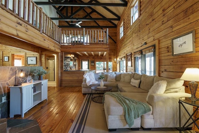 living room featuring hardwood / wood-style floors, beam ceiling, and wood walls