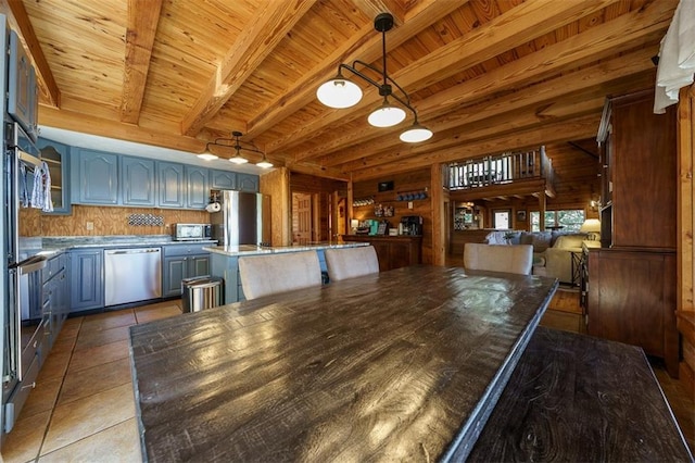 kitchen with wood ceiling, appliances with stainless steel finishes, a kitchen island, light tile patterned flooring, and dark stone counters