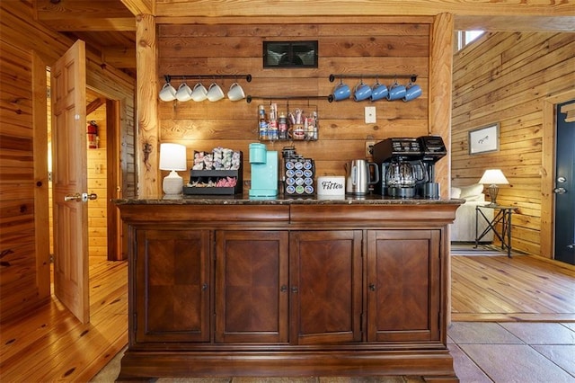 bar with tile patterned flooring, dark stone countertops, and wooden walls