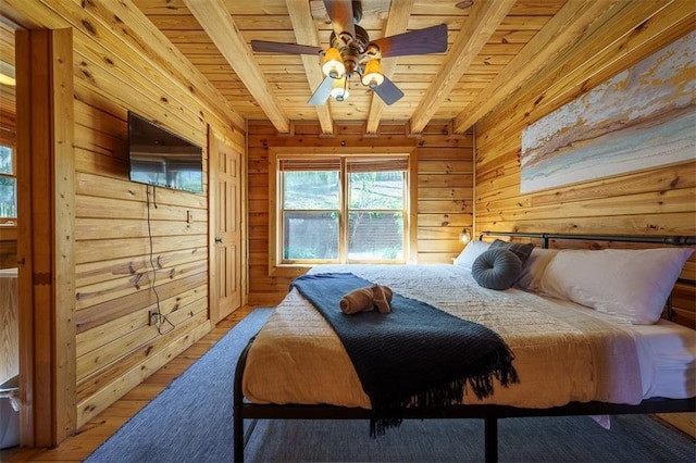 bedroom featuring wood ceiling, wooden walls, beamed ceiling, ceiling fan, and hardwood / wood-style floors