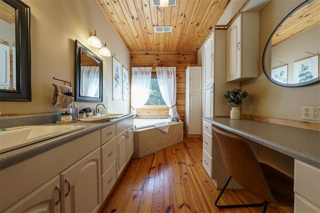 bathroom featuring vanity, hardwood / wood-style floors, wooden ceiling, and tiled tub