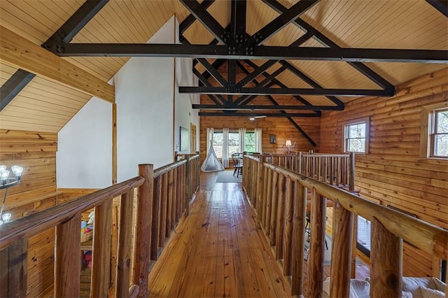 hallway featuring wood-type flooring, high vaulted ceiling, wooden walls, and beam ceiling