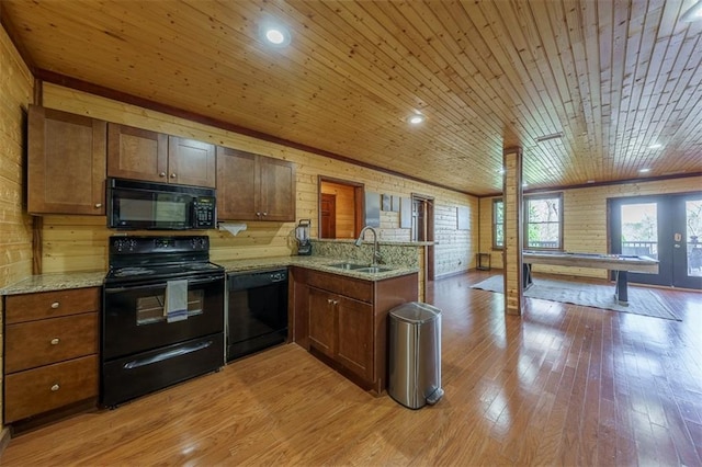 kitchen with sink, light stone counters, wooden ceiling, kitchen peninsula, and black appliances