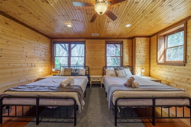 carpeted bedroom with wooden walls, multiple windows, and wooden ceiling