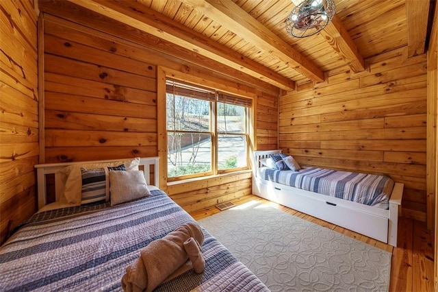 bedroom featuring wooden walls, wood-type flooring, beam ceiling, and wooden ceiling