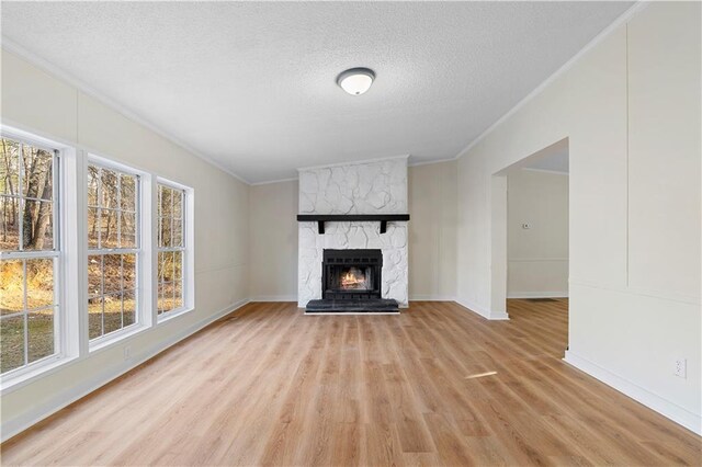 32 Brent Cir SW, Cartersville, GA 30120 - unfurnished living room featuring crown molding, baseboards, light wood-type flooring, a stone fireplace, and a textured ceiling