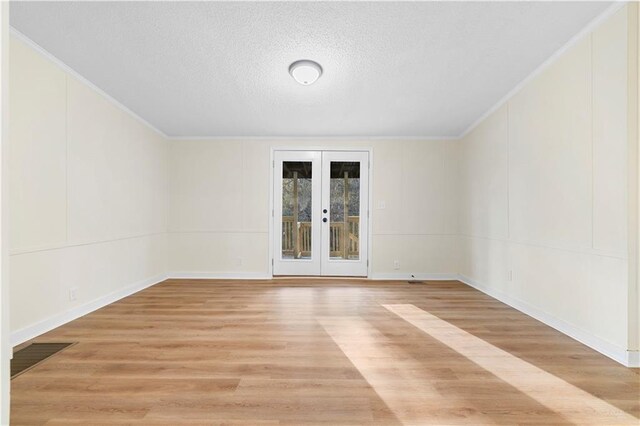 32 Brent Cir SW, Cartersville, GA 30120 - empty room featuring light wood finished floors, a textured ceiling, french doors, crown molding, and a decorative wall