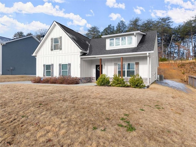 view of front of home with a front yard, covered porch, and cooling unit