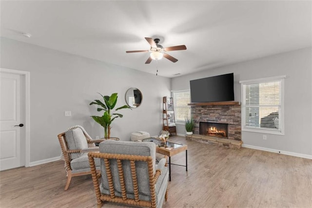 living room with light hardwood / wood-style floors, plenty of natural light, ceiling fan, and a stone fireplace