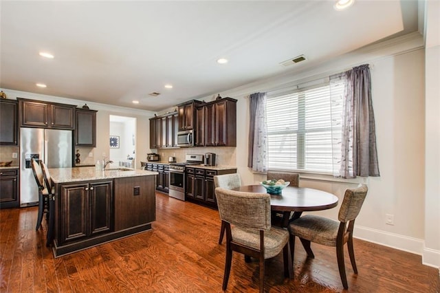 555 Lance View Ln, Lawrenceville, GA 30045 - kitchen with stainless steel appliances, crown molding, dark brown cabinetry, tasteful backsplash, and recessed lighting