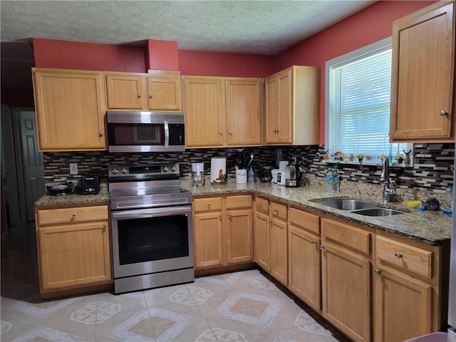 kitchen with tasteful backsplash, a textured ceiling, appliances with stainless steel finishes, and a sink