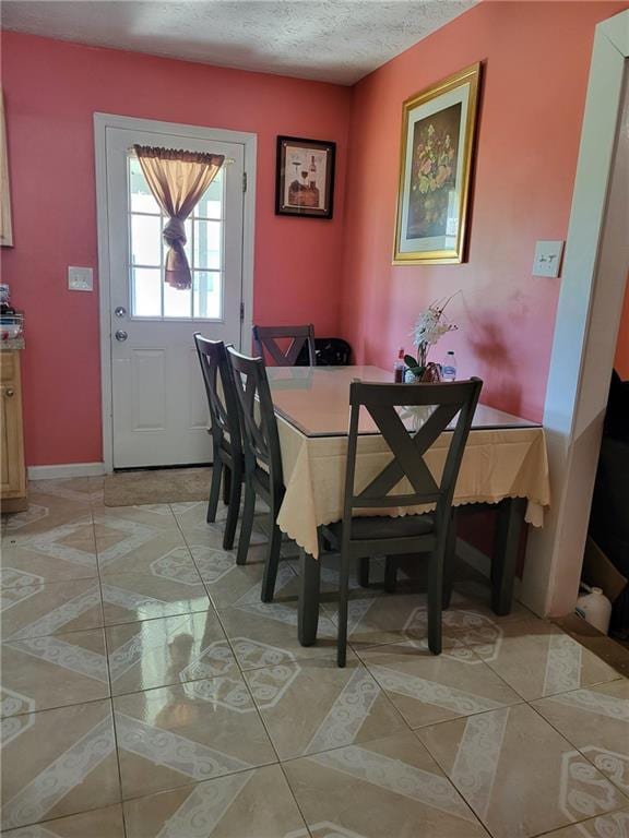dining area with light tile patterned floors, a textured ceiling, and baseboards
