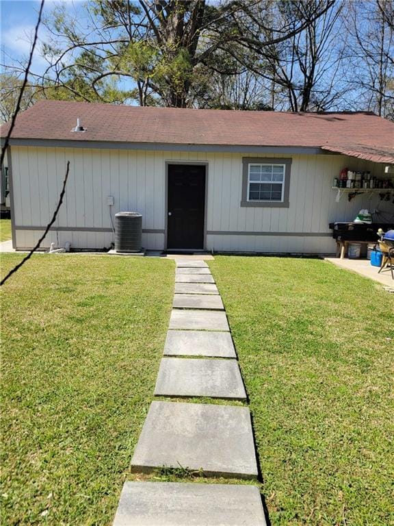 exterior space with a patio, cooling unit, a front yard, and roof with shingles