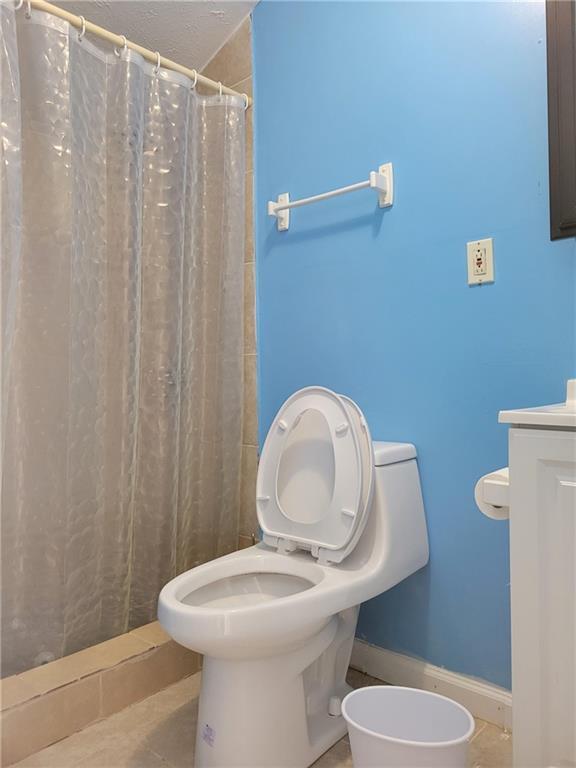full bath featuring tile patterned floors, curtained shower, and toilet
