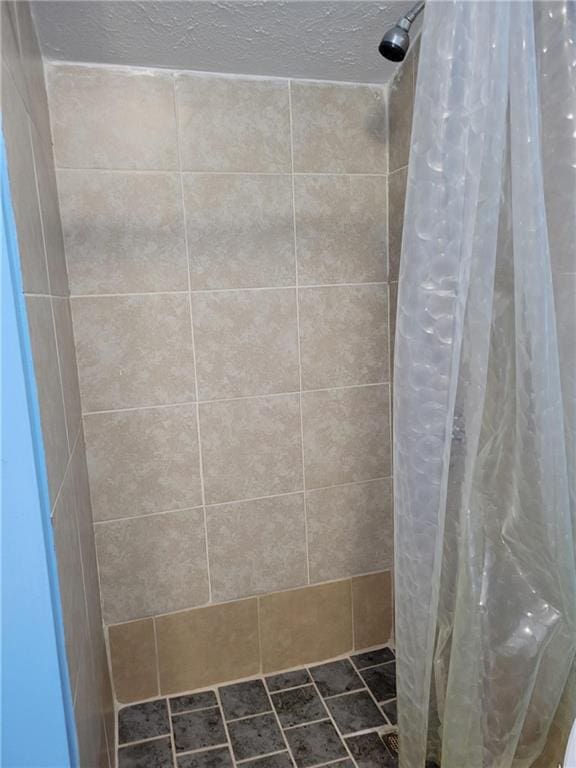 bathroom with a tile shower and a textured ceiling