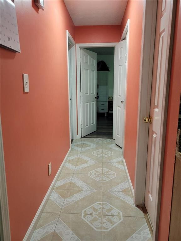 hall featuring light tile patterned floors and baseboards