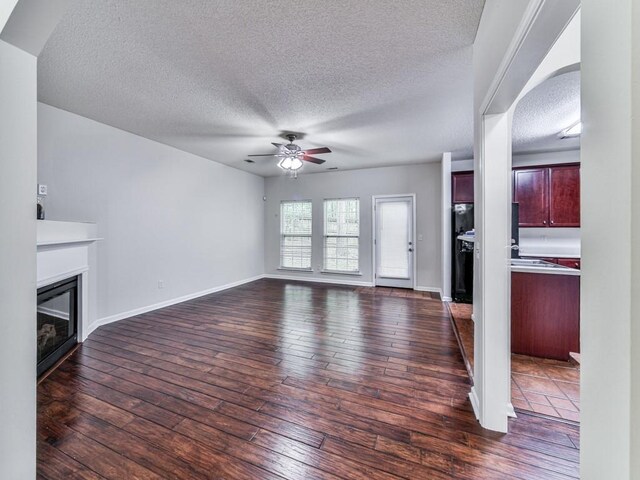 20 Preserve Dr, Newnan, GA 30263 - unfurnished living room featuring a ceiling fan, a textured ceiling, a glass covered fireplace, and dark wood-style floors