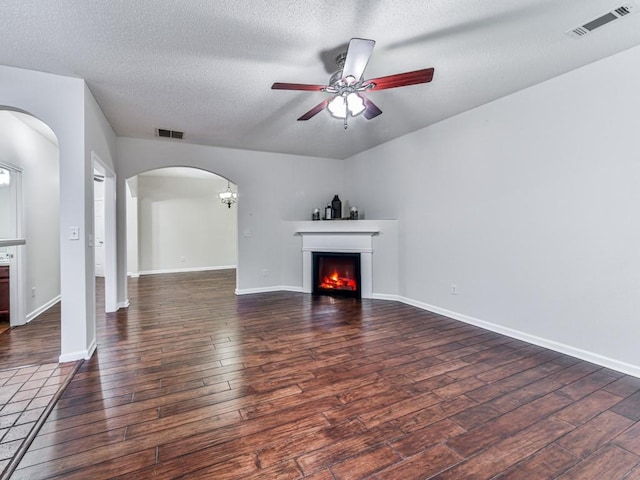 20 Preserve Dr, Newnan, GA 30263 - unfurnished living room featuring arched walkways, a ceiling fan, wood finished floors, a textured ceiling, and a warm lit fireplace