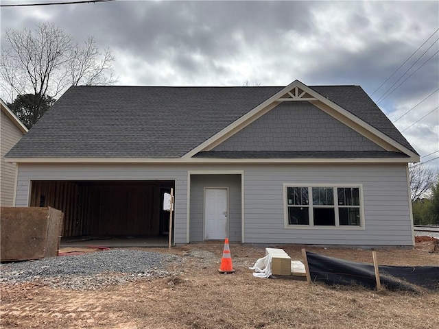view of front of property featuring a garage, driveway, and a shingled roof