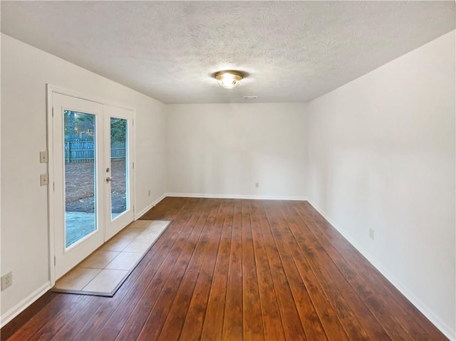 empty room with french doors, a textured ceiling, and wood-type flooring