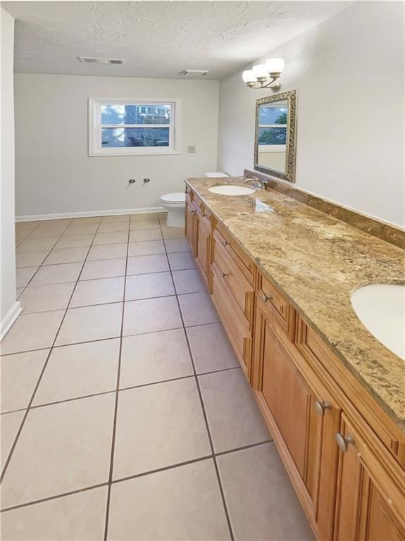 bathroom featuring vanity, toilet, tile patterned floors, and a textured ceiling