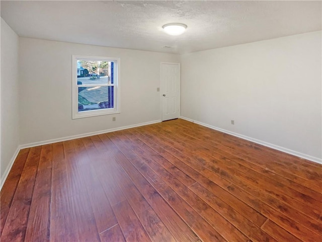 empty room with hardwood / wood-style floors and a textured ceiling