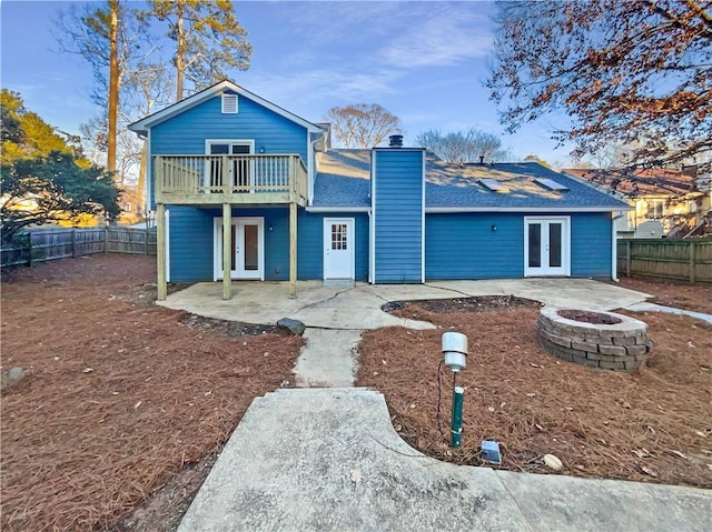 back of house with a balcony, an outdoor fire pit, a patio, and french doors