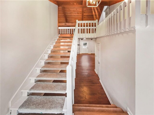 stairway featuring wood-type flooring, wooden ceiling, and high vaulted ceiling