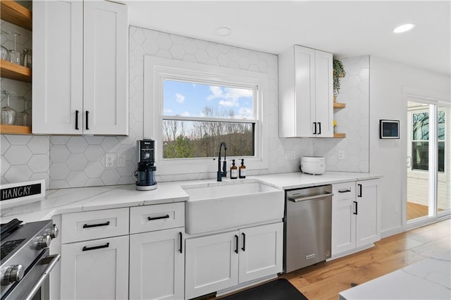 kitchen with stainless steel appliances, light stone countertops, decorative backsplash, sink, and white cabinetry