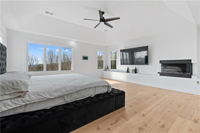 bedroom with a tray ceiling, ceiling fan, and light wood-type flooring