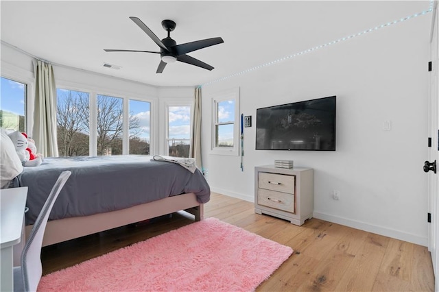 bedroom with multiple windows, ceiling fan, and light hardwood / wood-style floors