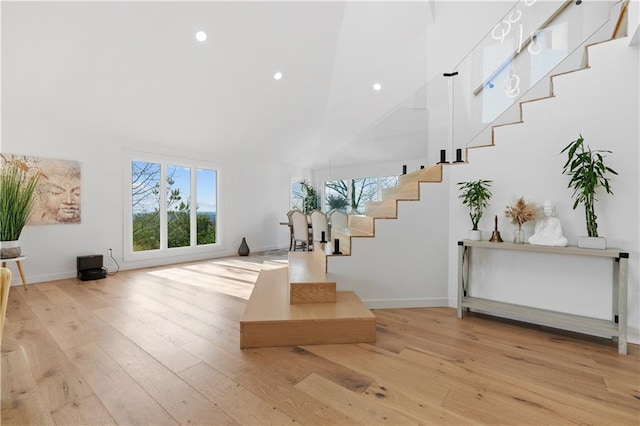 entryway with light hardwood / wood-style floors and high vaulted ceiling