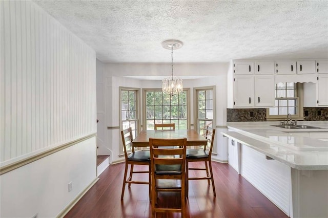 dining area featuring a textured ceiling, a notable chandelier, and dark wood-style floors