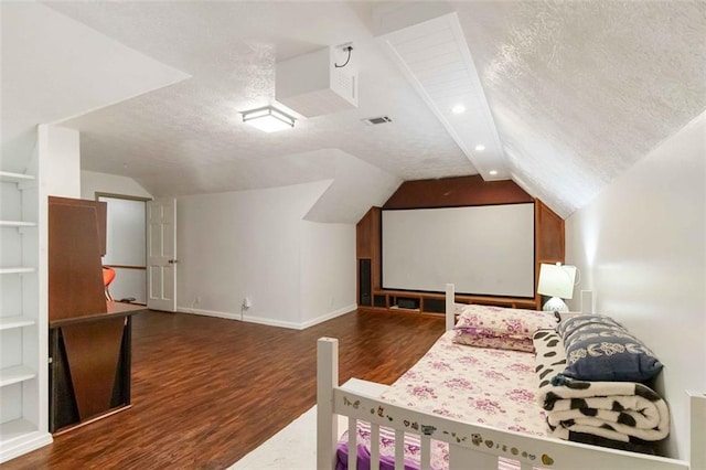 bedroom featuring visible vents, wood finished floors, baseboards, a textured ceiling, and vaulted ceiling