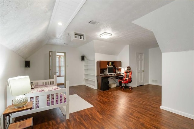 bedroom with visible vents, lofted ceiling, wood finished floors, baseboards, and a textured ceiling