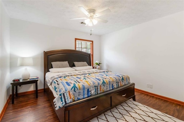 bedroom featuring baseboards, a textured ceiling, wood finished floors, and visible vents