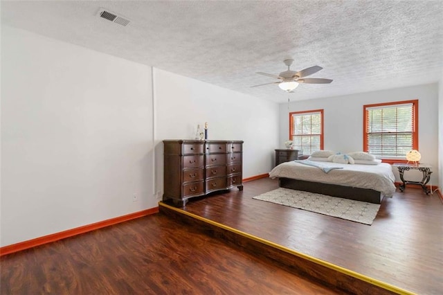 bedroom with visible vents, wood finished floors, baseboards, a textured ceiling, and a ceiling fan