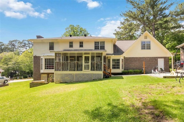 rear view of house with a lawn, a chimney, a sunroom, and brick siding