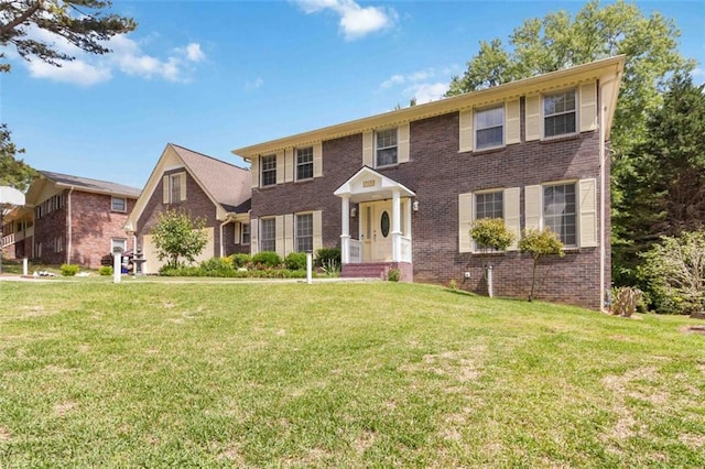colonial inspired home with brick siding and a front yard